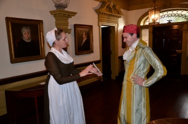woman and man in historical clothing looking at a book
